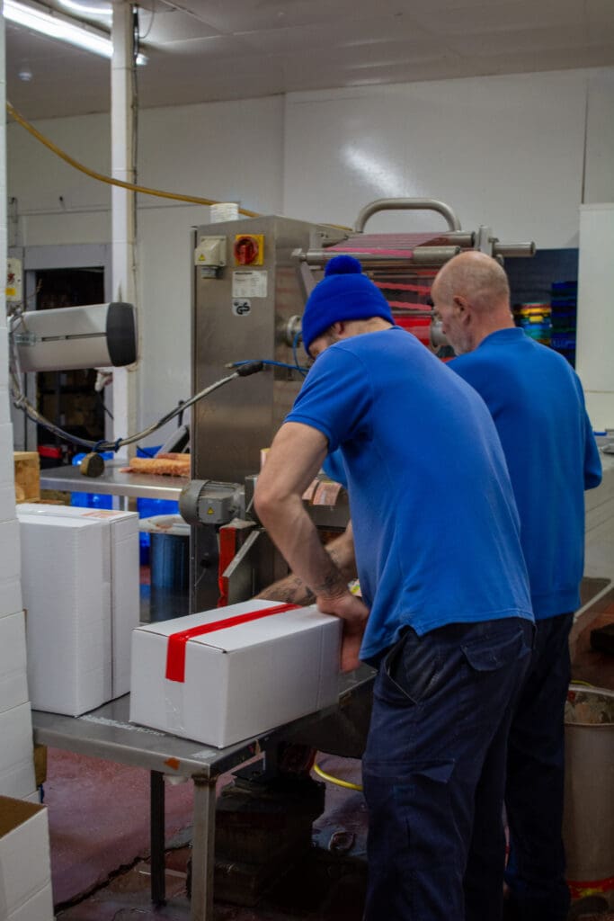 Worker sealing a delivery box of bacon